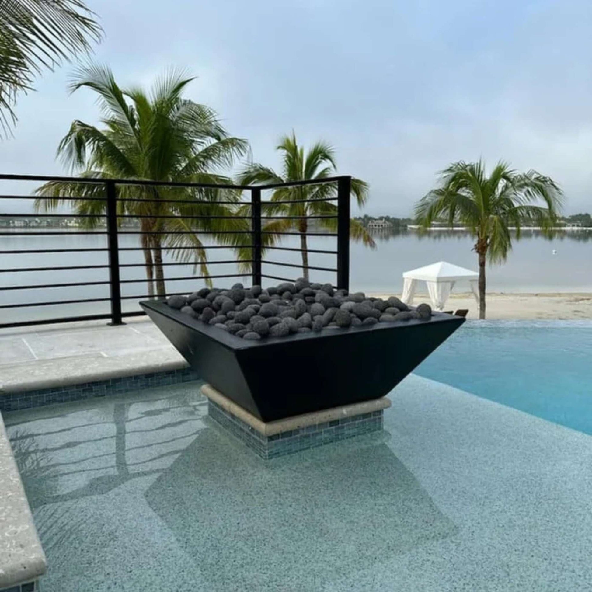 Grand Effects Corinthian Fire Bowl in Concrete at luxury poolside, featuring black lava rocks, SKU: SOS Pool.