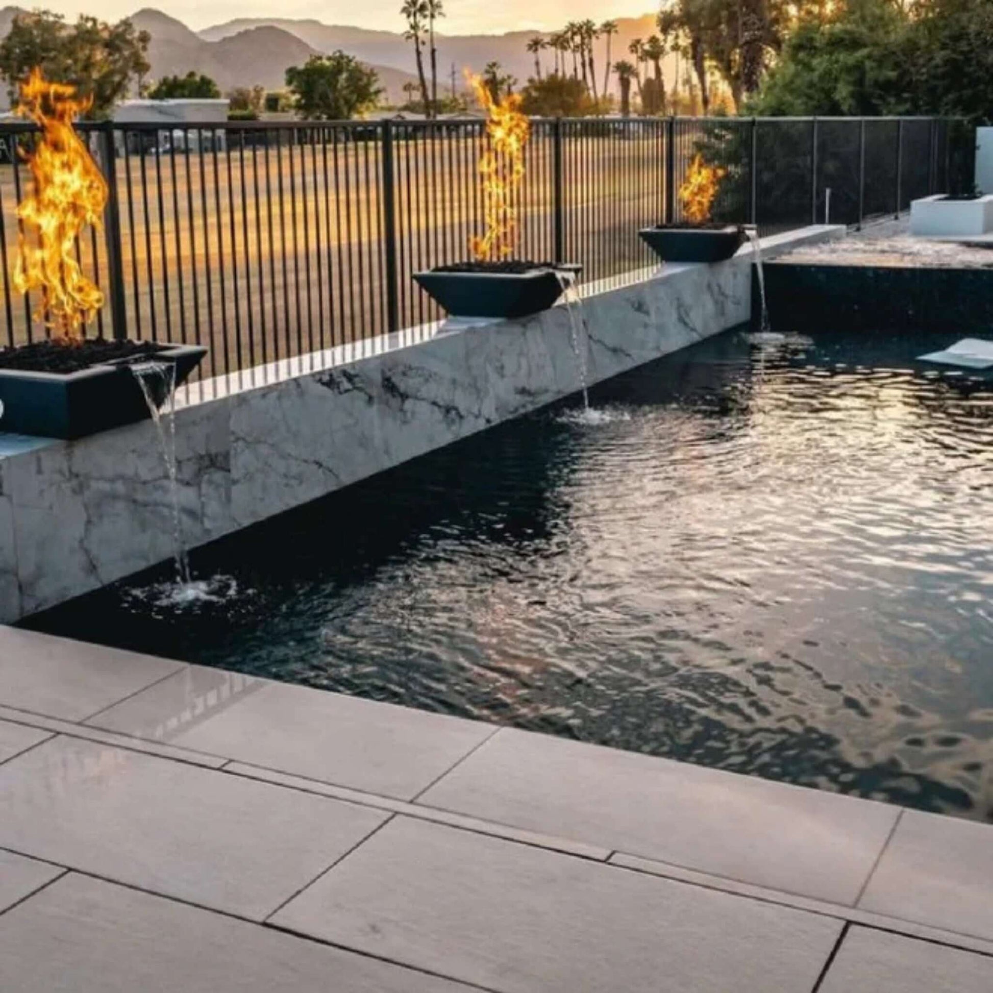 Luxurious pool with fire and water bowls at sunset featuring Grand Effects Corinthian Fire & Water Bowl by SOS Pool.