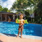 A toddler standing by a pool, wearing Dinosaur Arm Bands, enjoying water play, product SKU: 32132J, SOS Pool.