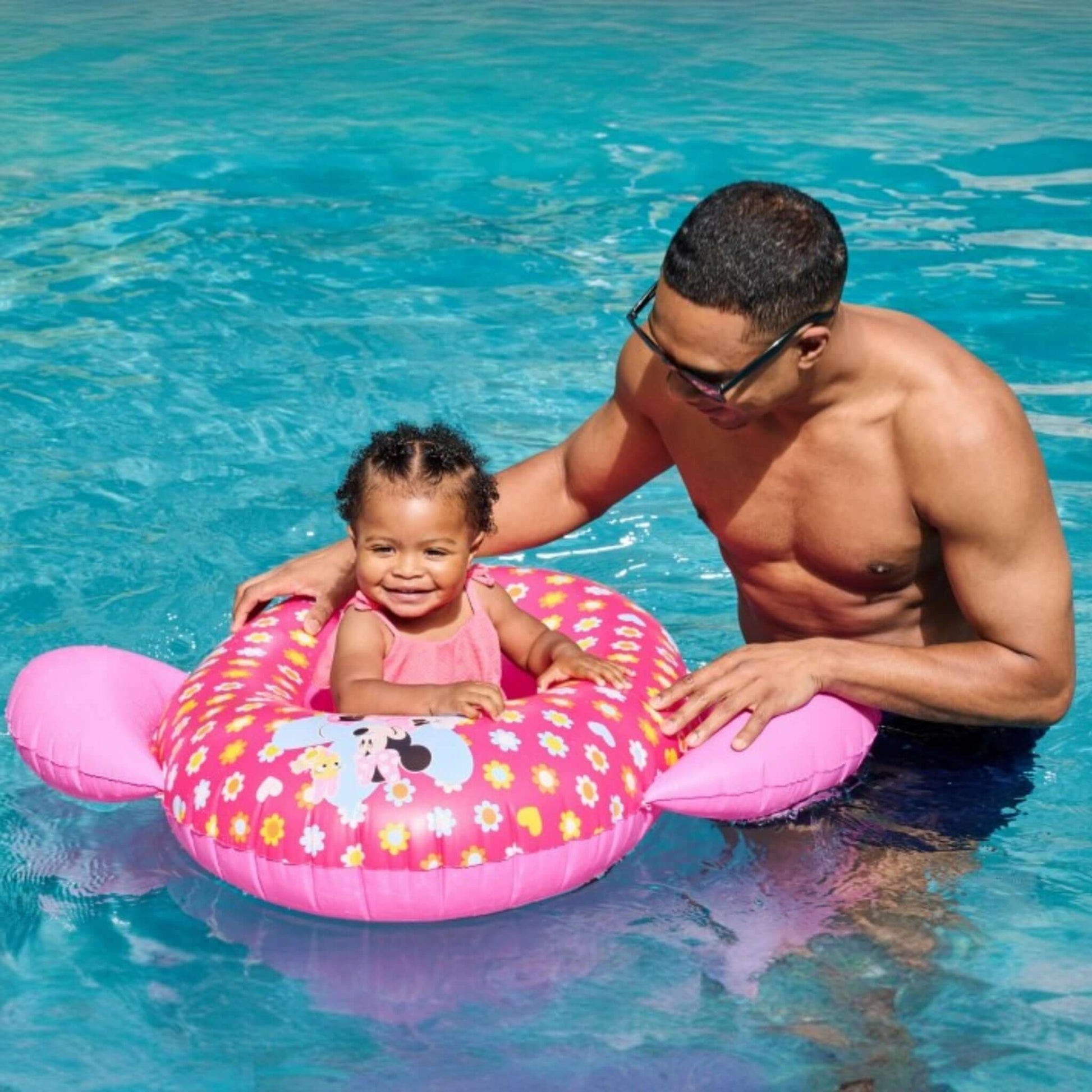 Child enjoying the SwimWays Minnie Inflatable Baby Boat in the pool with an adult, SKU 6071745, SOS Pool.