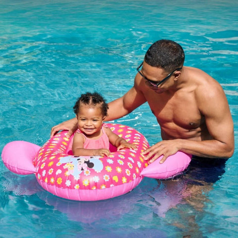 Child enjoying the SwimWays Minnie Inflatable Baby Boat in the pool with an adult, SKU 6071745, SOS Pool.
