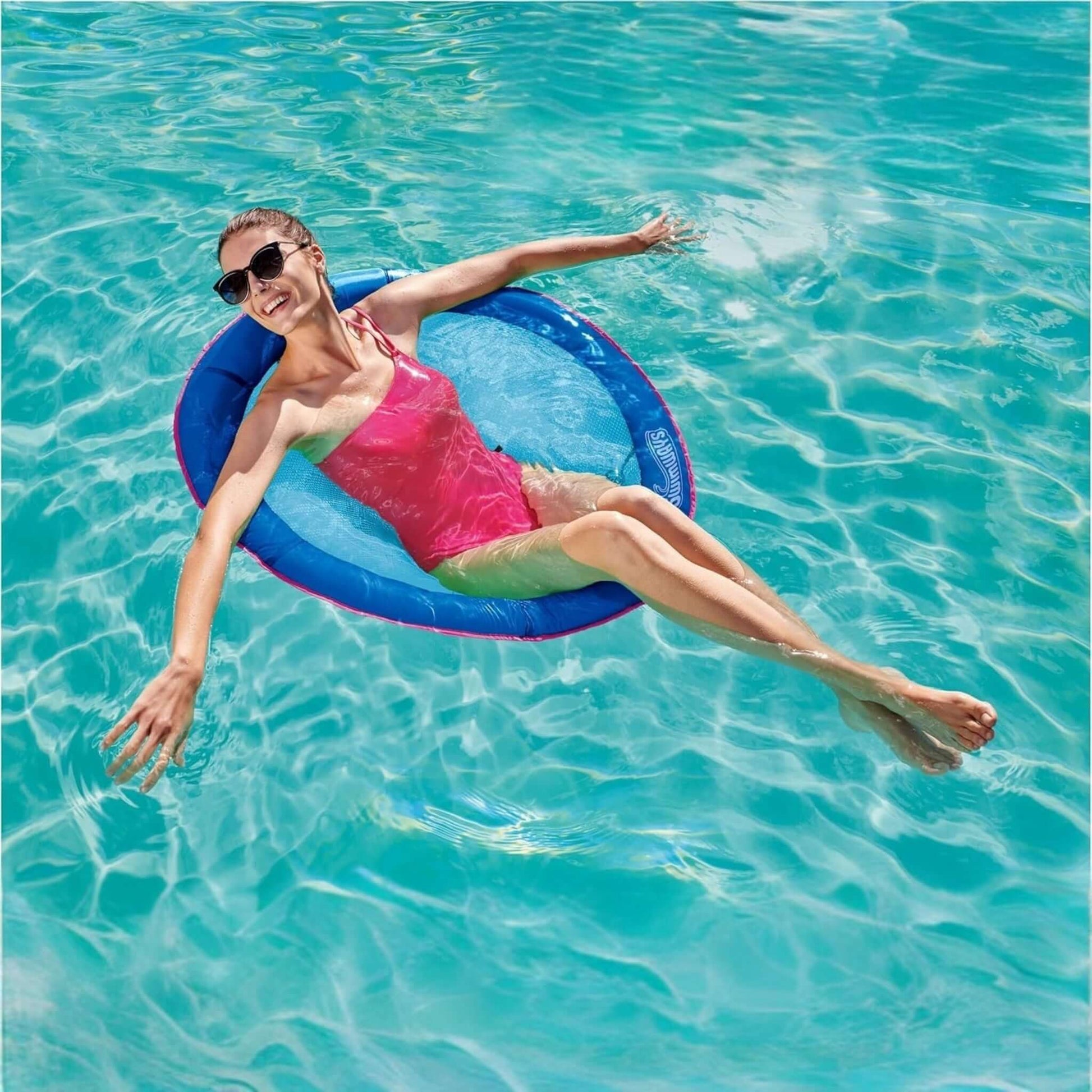 Woman relaxing on SwimWays Premium Spring Float Papasan in clear water, SKU 6069494, great for SOS Pool fun.