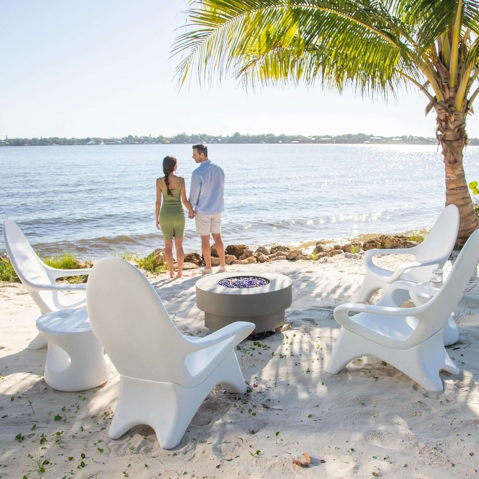 Couple enjoying a beachfront view with TenJam chairs around a fire pit, ideal for relaxation by the water.